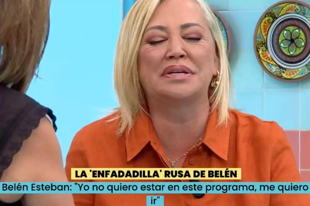 Una dona amb cabell ros i camisa taronja apareix en un programa de televisió, amb els ulls tancats i una expressió facial que suggereix frustració o descontentament. Una dona amb cabell ros i camisa taronja apareix en un programa de televisió, amb els ulls tancats i una expressió facial que suggereix frustració o descontentament.