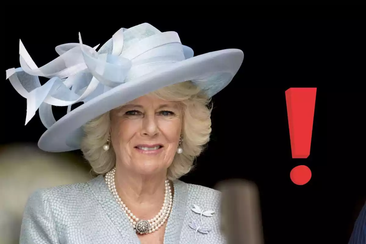 Blonde-haired woman with a light blue hat and pearl necklace posing next to a large red exclamation mark against a black background