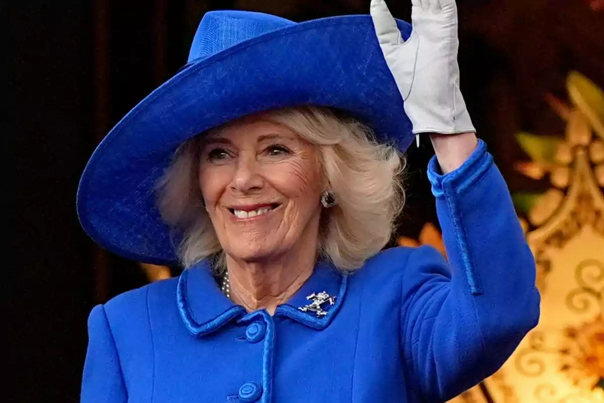 Una dona somrient amb barret i abric blau saludant amb la mà. Una dona somrient amb barret i abric blau saludant amb la mà.