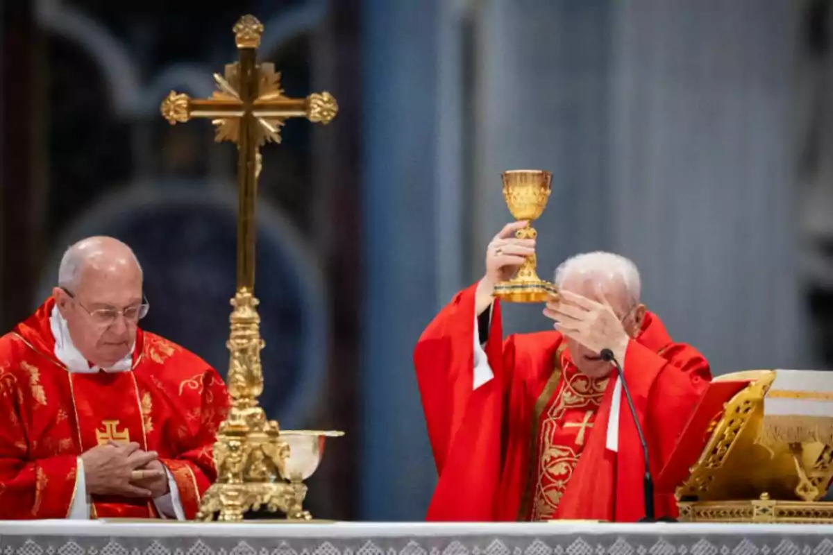 Two clerics dressed in red garments perform a religious ritual at an altar adorned with golden objects.