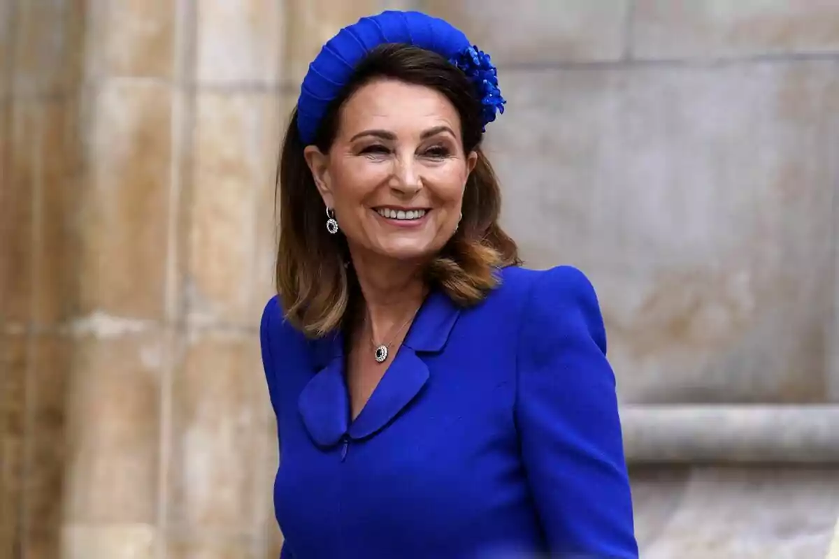 A smiling woman in a blue dress with a matching headpiece.