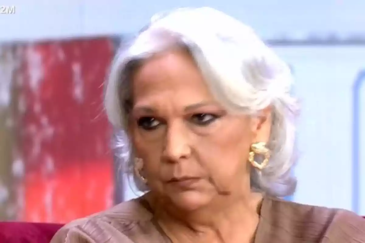 Una persona de cabells blancs i expressió seriosa està en un entorn interior. Una persona de cabells blancs i expressió seriosa està en un entorn interior.
