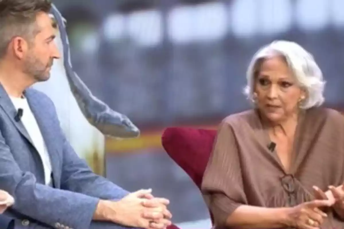 Dues persones assegudes en un plató de televisió, una d'elles amb cabells blancs i l'altra amb barba, ambdues amb micròfons de solapa. Dues persones assegudes en un plató de televisió, una d'elles amb cabells blancs i l'altra amb barba, ambdues amb micròfons de solapa.