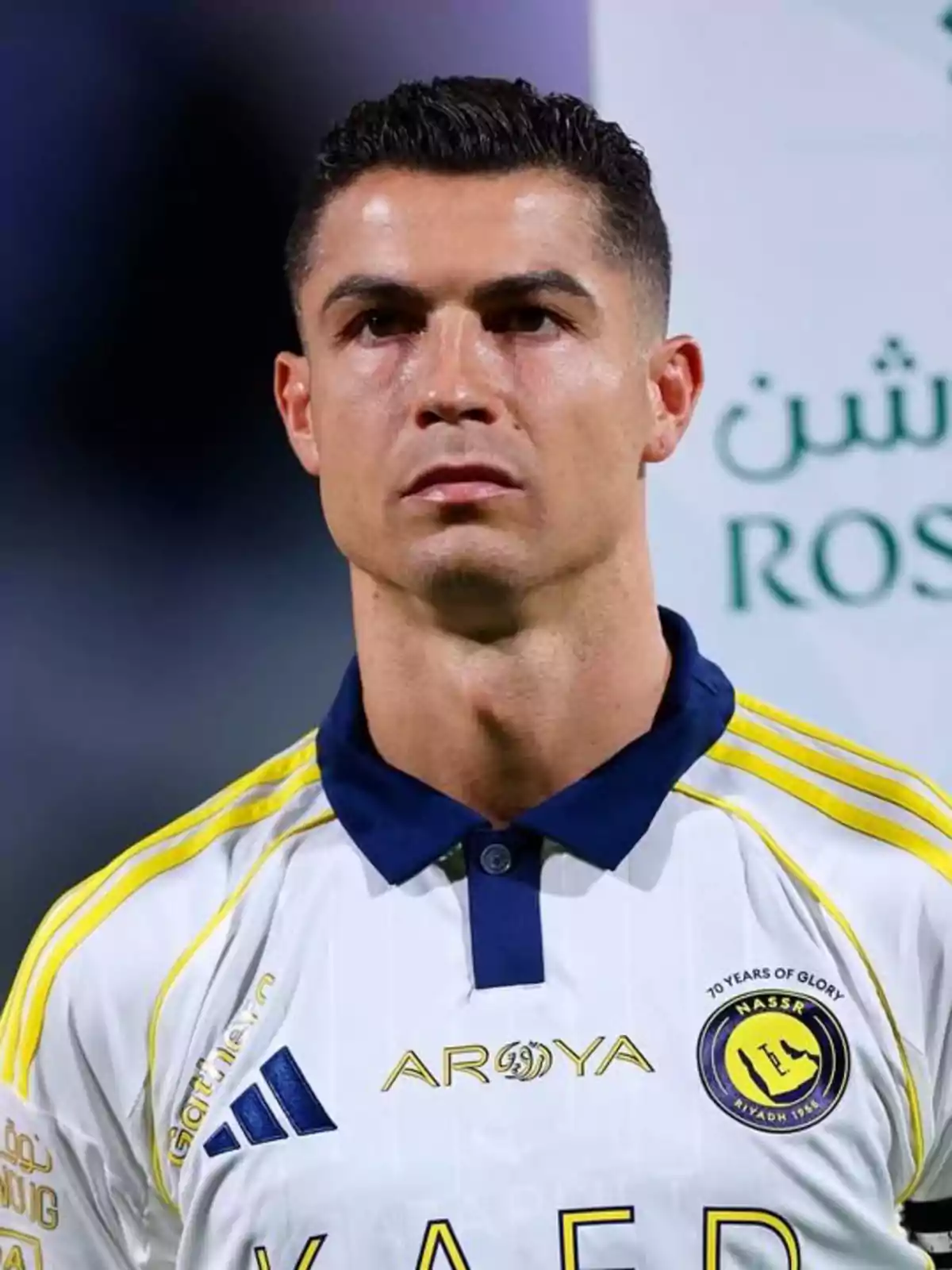 Cristiano Ronaldo con uniforme blanco y detalles amarillos de un equipo saudí mirando al frente durante un evento deportivo Cristiano Ronaldo con uniforme blanco y detalles amarillos de un equipo saudí mirando al frente durante un evento deportivo