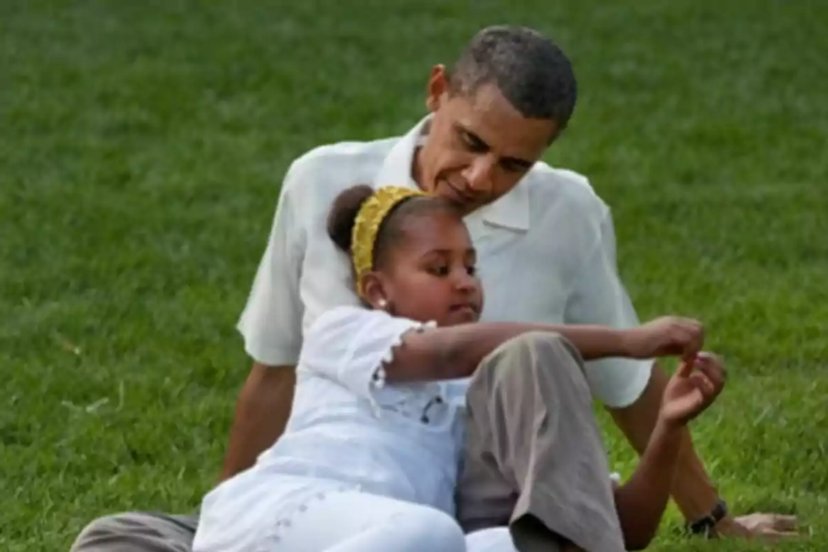 Barack Obama y su hija Michelle sentados en el césped disfrutando de un momento juntos. Barack Obama y su hija Michelle sentados en el césped disfrutando de un momento juntos.