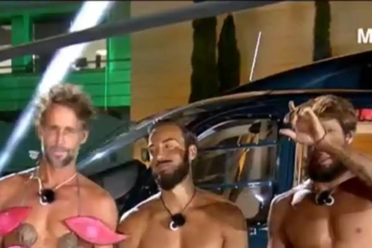 Escassi, Borja y Montoya posan frente a un helicóptero durante la noche, uno de ellos lleva accesorios rosas y otro hace un gesto con la mano. Escassi, Borja y Montoya posan frente a un helicóptero durante la noche, uno de ellos lleva accesorios rosas y otro hace un gesto con la mano.