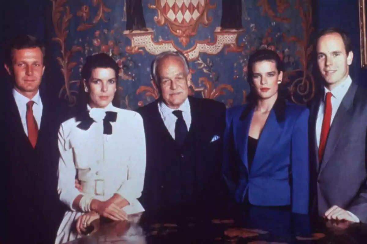 A group of five people posing together in front of a decorative background. A group of five people posing together in front of a decorative background.