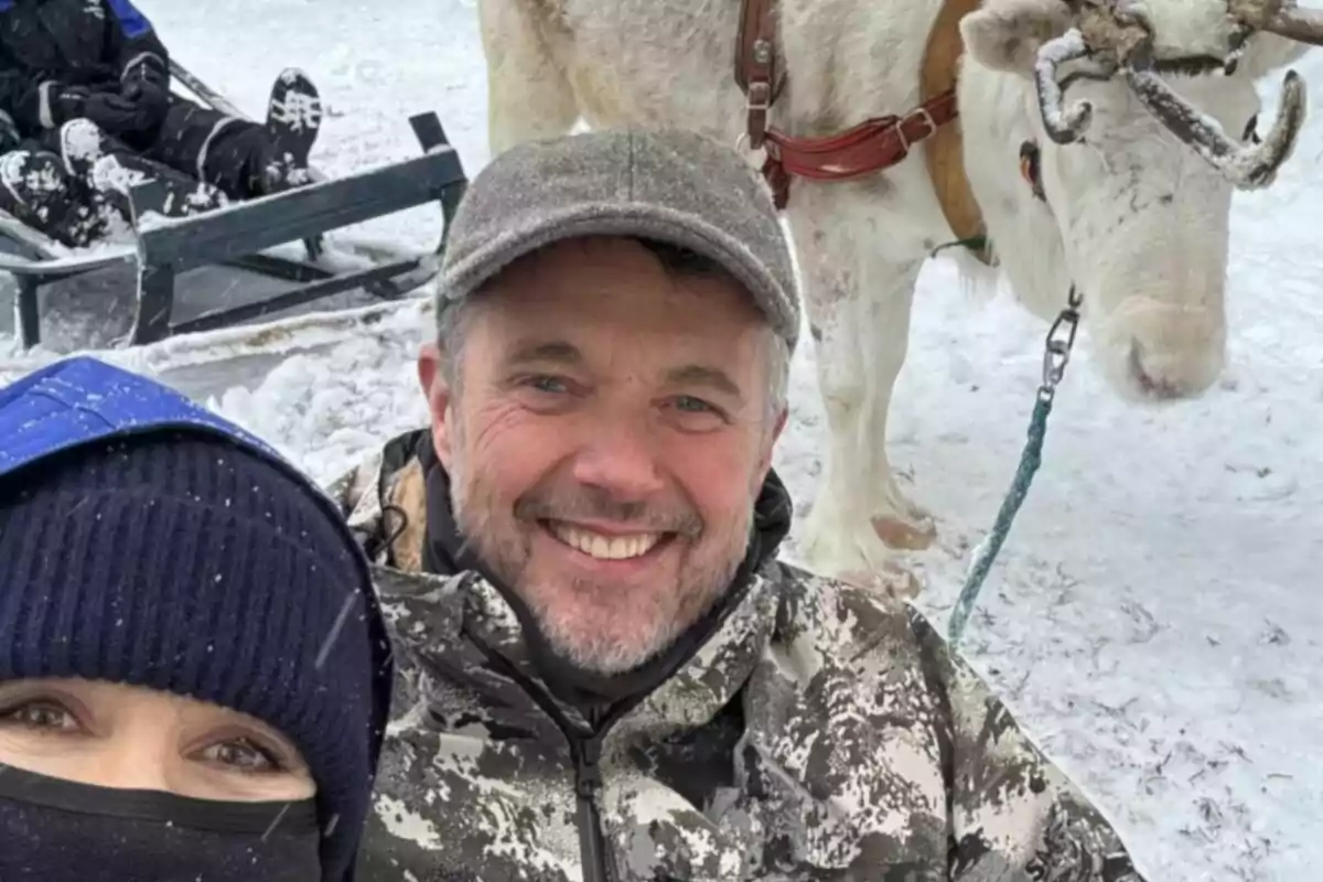 Persones somrients posant per a una foto a la neu al costat d'un ren. Persones somrients posant per a una foto a la neu al costat d'un ren.