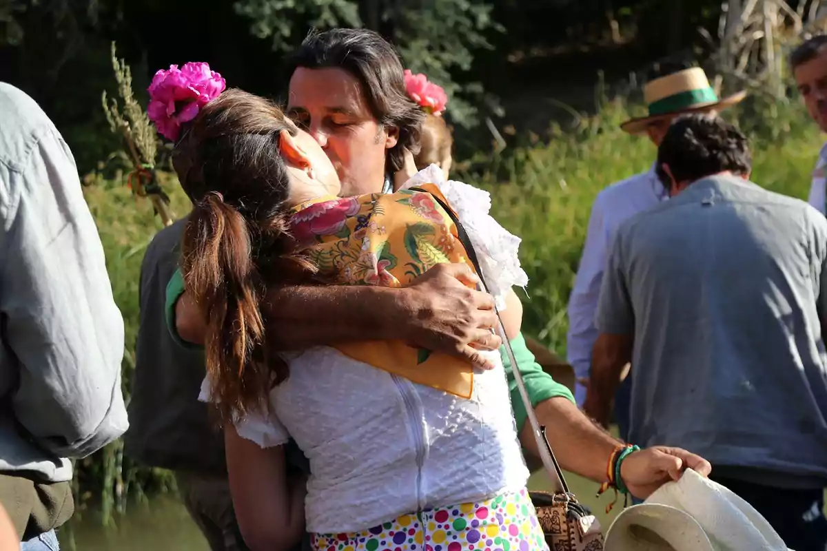 Couple dressed in traditional Andalusian clothing hug and kiss during an outdoor celebration surrounded by other people Couple dressed in traditional Andalusian clothing hug and kiss during an outdoor celebration surrounded by other people