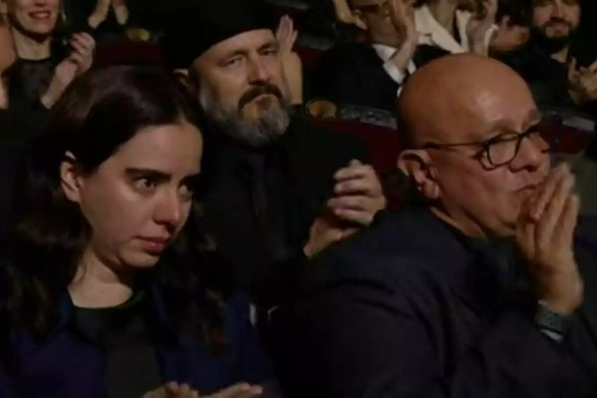 Persones en una audiència aplaudint mentre una dona en primer pla sembla emocionada. Persones en una audiència aplaudint mentre una dona en primer pla sembla emocionada.
