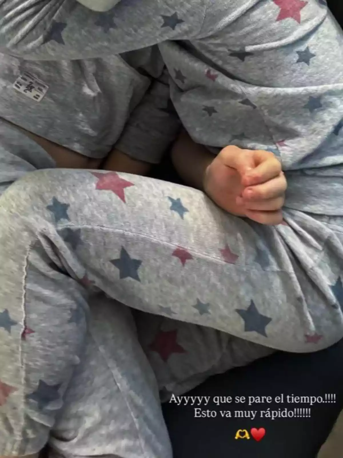 Una persona amb pijama gris amb estrelles de colors està abraçant un nen que porta un conjunt similar. Una persona amb pijama gris amb estrelles de colors està abraçant un nen que porta un conjunt similar.