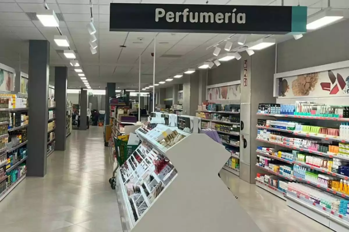 Passadís d'una botiga amb prestatges plens de productes de perfumeria i cosmètica, il·luminat amb llums de sostre.