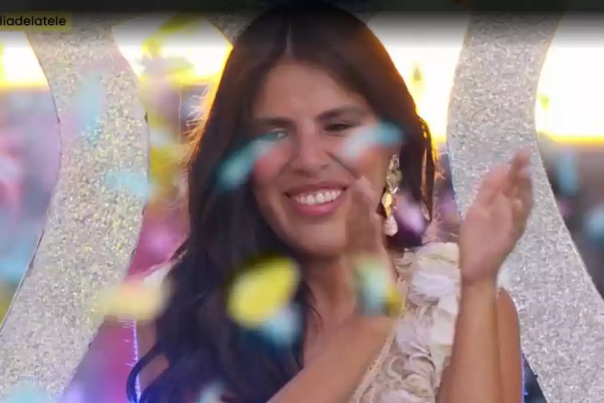 Una persona somrient aplaude mentre confeti de colors cau al seu voltant en un ambient festiu. Una persona somrient aplaude mentre confeti de colors cau al seu voltant en un ambient festiu.