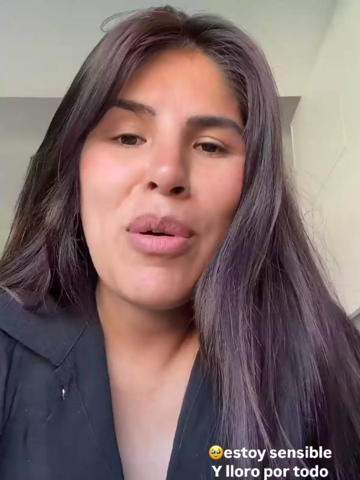 Una persona amb cabell llarg i fosc està parlant davant de la càmera, vestint una peça negra, amb un text a la part inferior que expressa estar sensible i plorar per tot. Una persona amb cabell llarg i fosc està parlant davant de la càmera, vestint una peça negra, amb un text a la part inferior que expressa estar sensible i plorar per tot.