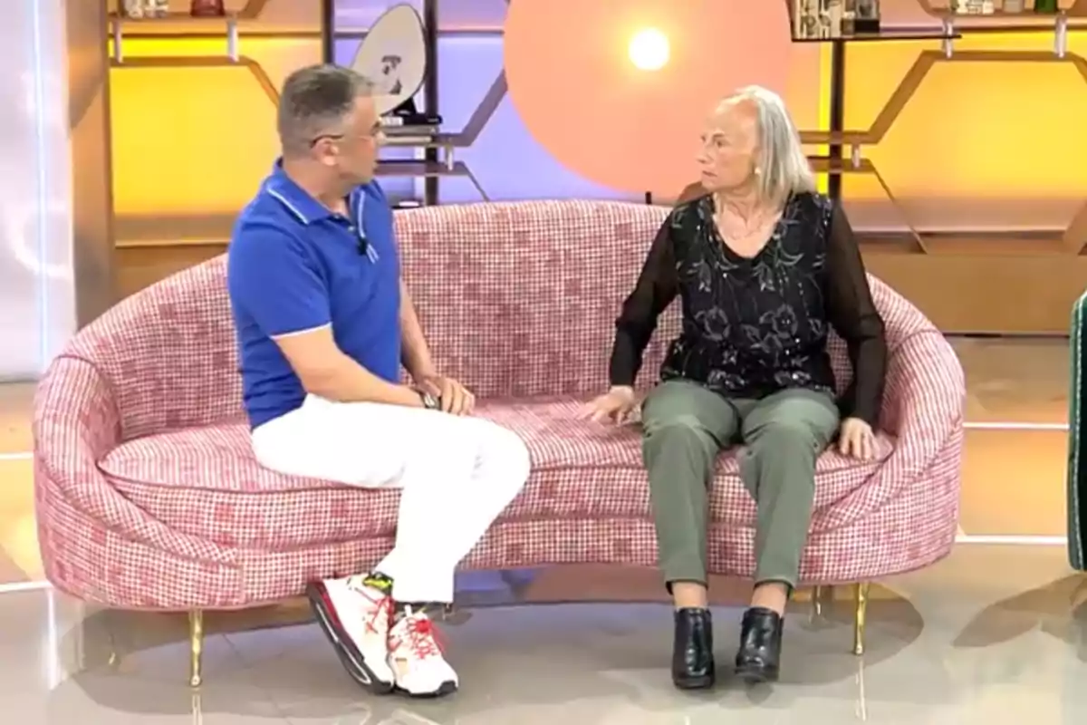Dues persones assegudes en un sofà durant un programa de televisió amb un fons il·luminat i decorat. Dues persones assegudes en un sofà durant un programa de televisió amb un fons il·luminat i decorat.