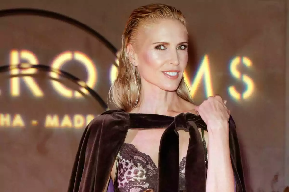 Una persona con cabello rubio y lacio, vestida con un atuendo elegante, posa frente a un fondo con luces brillantes. Una persona con cabello rubio y lacio, vestida con un atuendo elegante, posa frente a un fondo con luces brillantes.