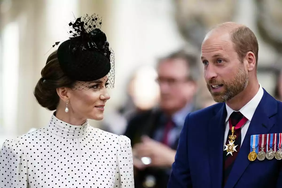 A woman in an elegant black hat and polka dot dress is talking to a man wearing a blue suit and several medals. A woman in an elegant black hat and polka dot dress is talking to a man wearing a blue suit and several medals.