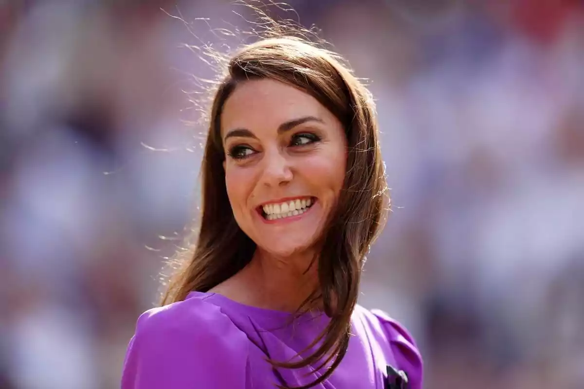 Young woman with long brown hair smiling and wearing a purple dress with a blurred background Young woman with long brown hair smiling and wearing a purple dress with a blurred background