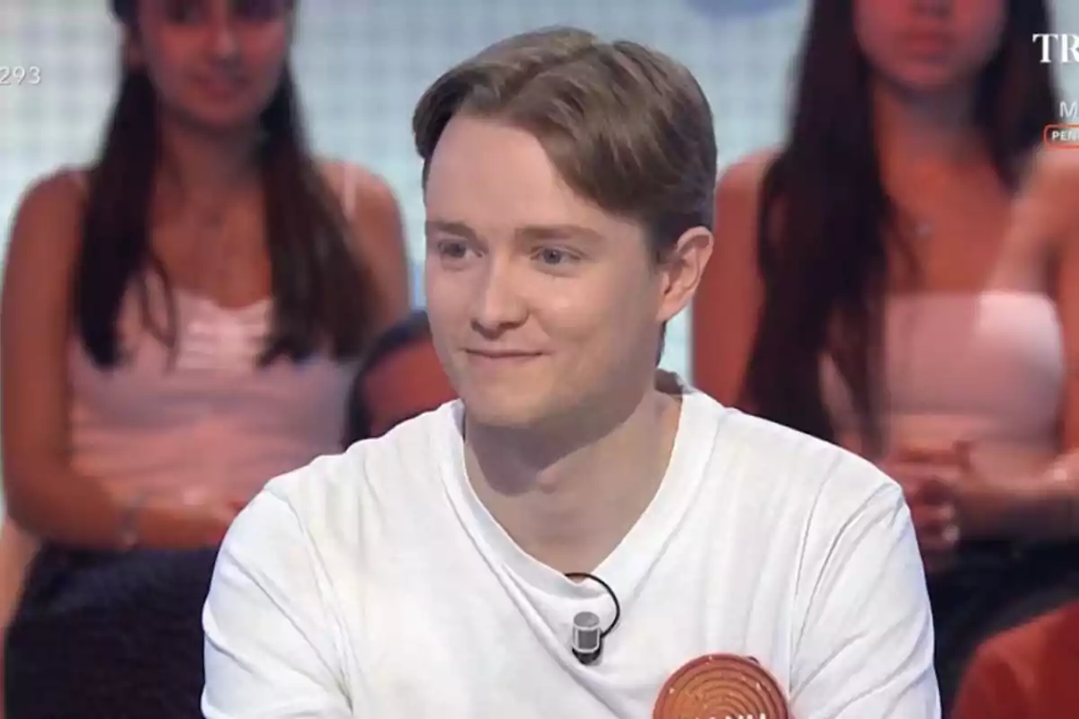 Jove de cabells clars i samarreta blanca participant en un programa de televisió amb públic al fons Jove de cabells clars i samarreta blanca participant en un programa de televisió amb públic al fons