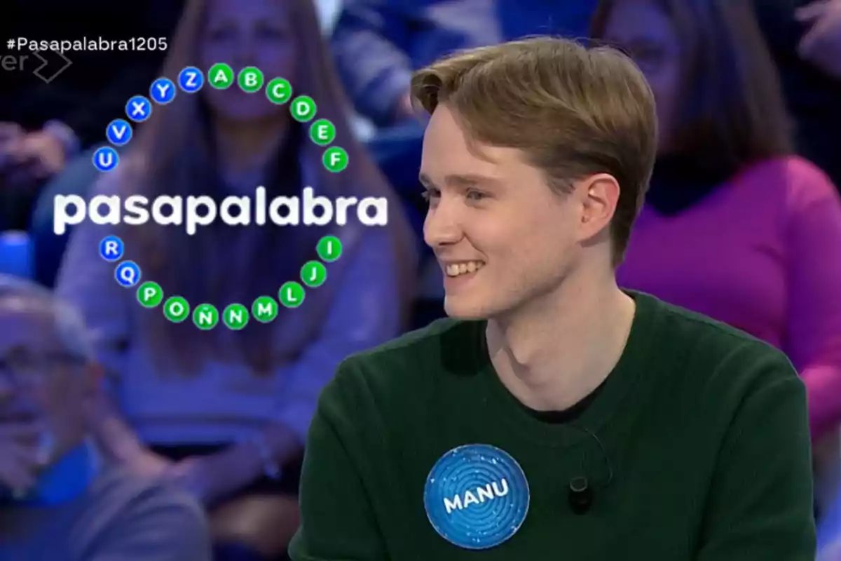 Un concursant somriu mentre participa en el programa de televisió "Pasapalabra", amb un cercle de lletres al fons.