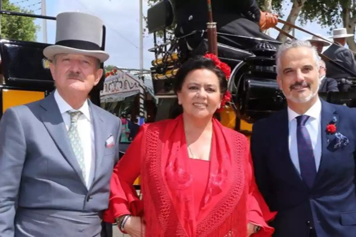 Tres persones posen elegantment vestides davant d'un carruatge en un esdeveniment a l'aire lliure. Tres persones posen elegantment vestides davant d'un carruatge en un esdeveniment a l'aire lliure.