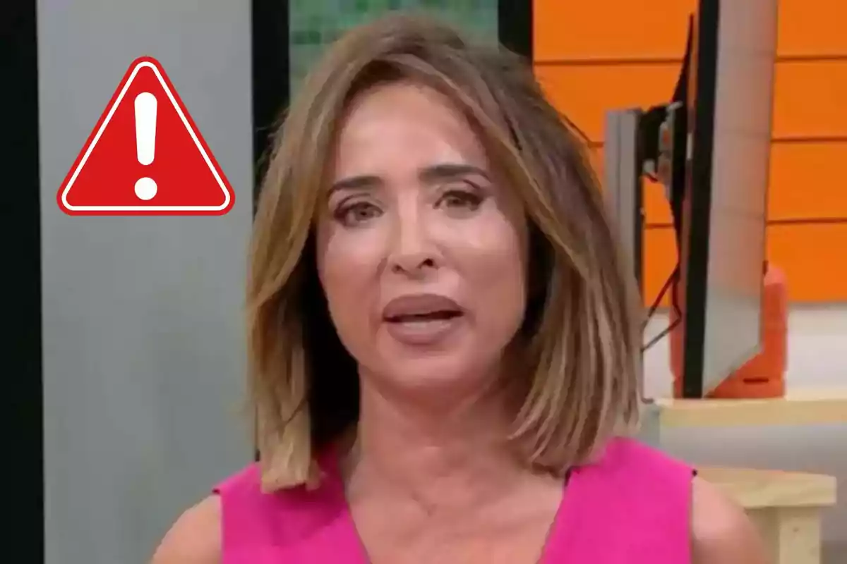 Dona amb expressió seriosa en un estudi de televisió amb un símbol d'advertència vermell al seu costat