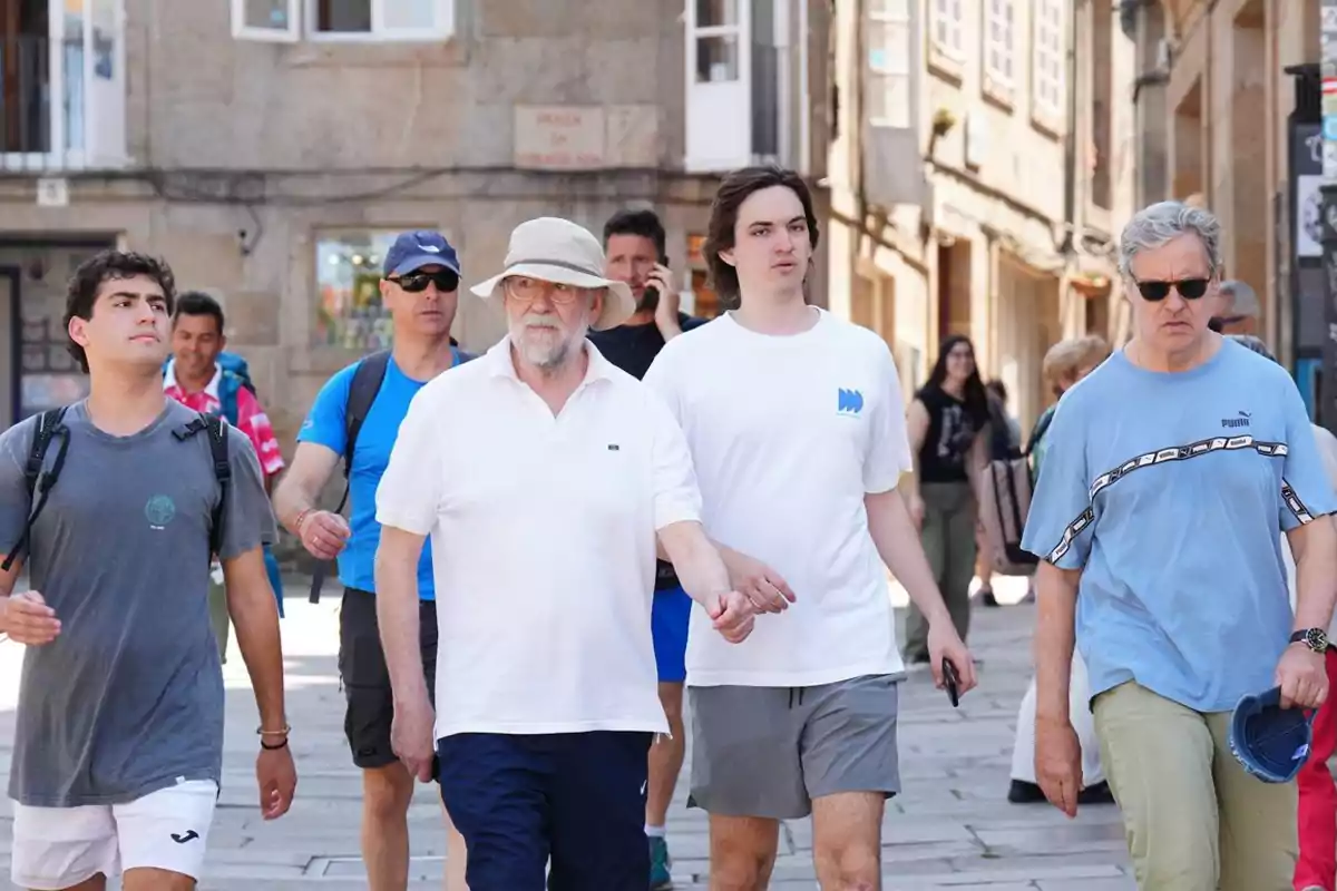 Grup de persones caminant per un carrer de vianants en una ciutat antiga en un dia assolellat Grup de persones caminant per un carrer de vianants en una ciutat antiga en un dia assolellat