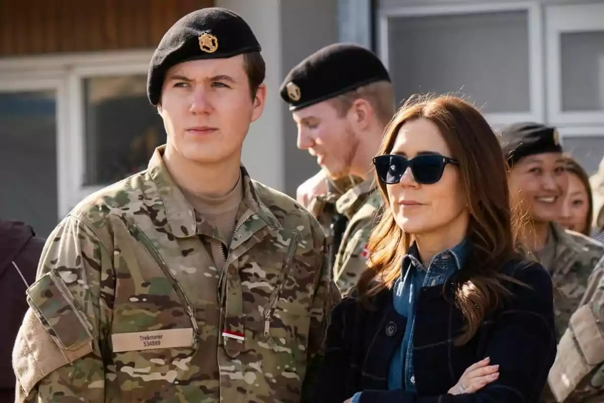 Un grupo de personas vestidas con uniformes militares, una de ellas lleva gafas de sol y está de pie junto a un soldado. Un grupo de personas vestidas con uniformes militares, una de ellas lleva gafas de sol y está de pie junto a un soldado.
