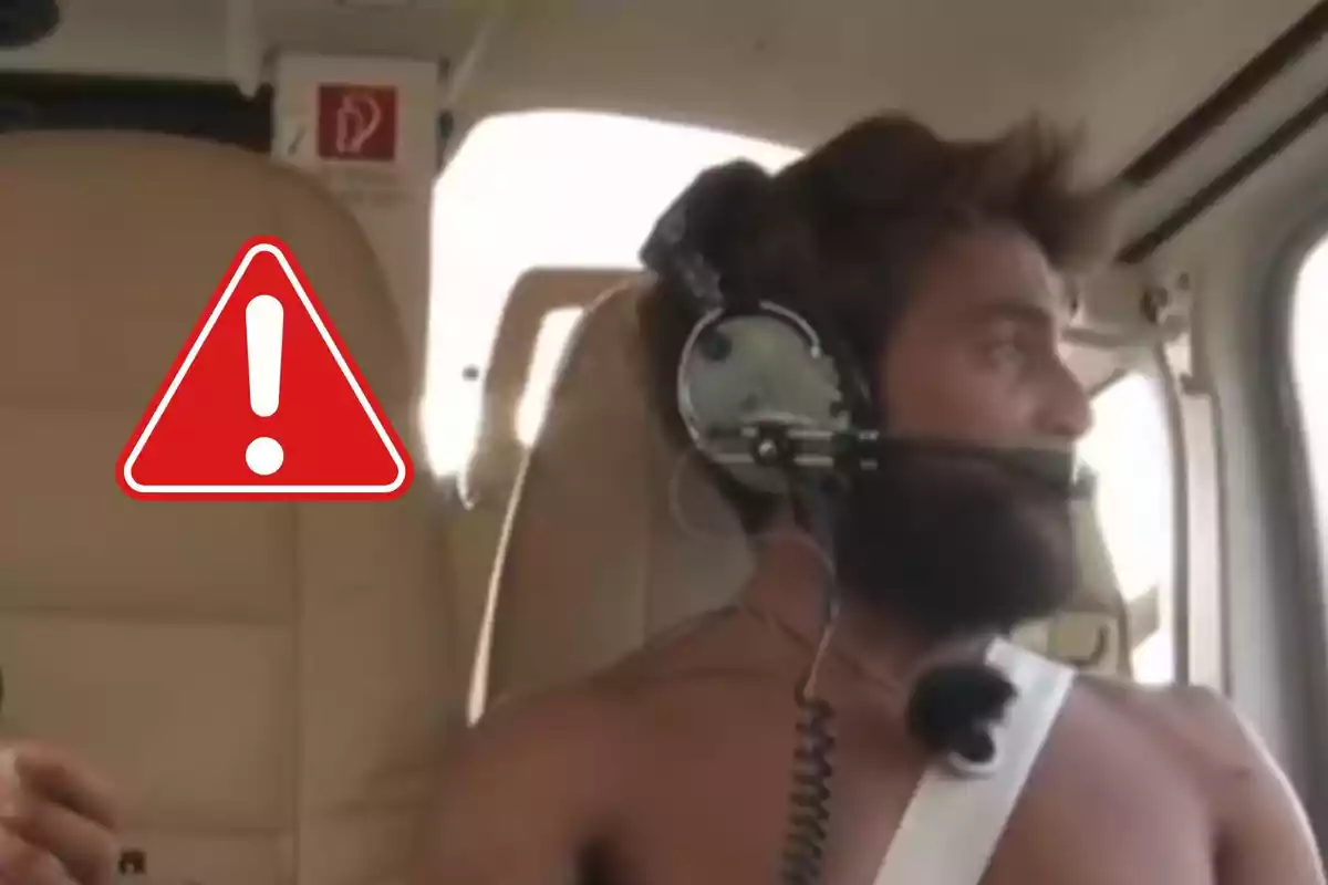 Home amb auriculars i micròfon dins d’una cabina d’helicòpter sense samarreta i un símbol d’advertència a la imatge