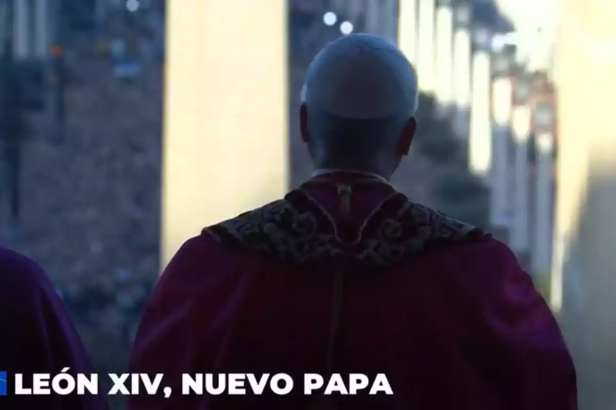 Un home vestit amb indumentària papal observa des d'un balcó. Un home vestit amb indumentària papal observa des d'un balcó.