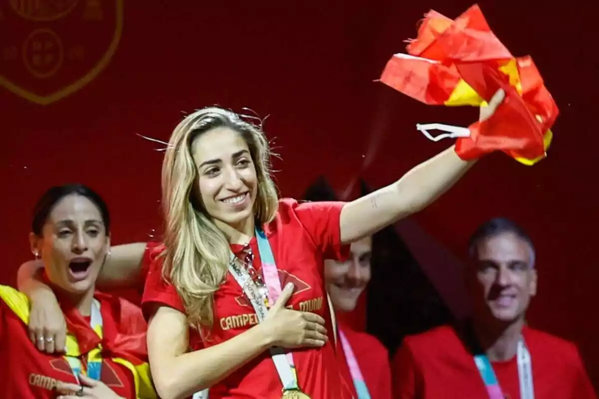 Imatge d'Olga Carmona feliç amb una mà al pit i l'altra aixecant la bandera espanyola durant la celebració a Madrid de la victòria de la Selecció Espanyola Femenina al Mundial Femení 2023