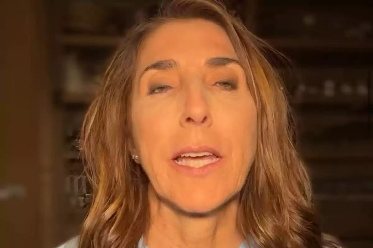 Dona de cabell castany clar i ondulat parlant davant de la càmera amb un fons desenfocat en interiors Dona de cabell castany clar i ondulat parlant davant de la càmera amb un fons desenfocat en interiors