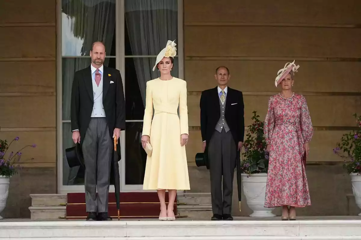 Un grup de persones elegantment vestides posant en una escala davant d'un edifici amb grans finestres i testos amb flors. Un grup de persones elegantment vestides posant en una escala davant d'un edifici amb grans finestres i testos amb flors.