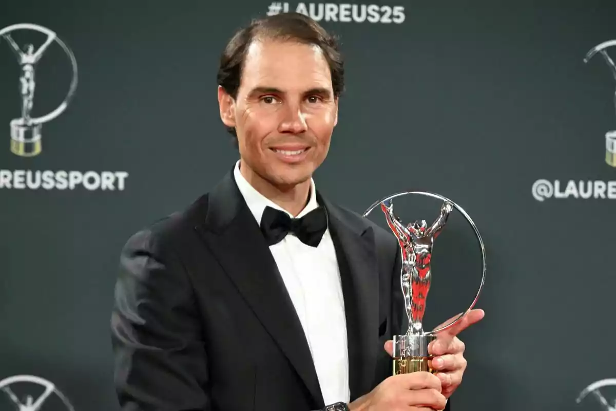 A man in a tuxedo holds a trophy at a sports awards event. A man in a tuxedo holds a trophy at a sports awards event.