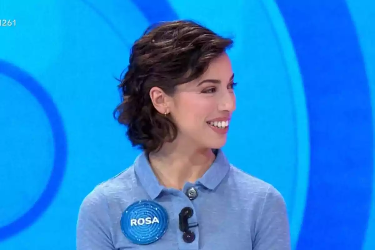 Una persona amb cabell curt i fosc somriu mentre porta una camisa blava amb un botó i un micròfon en un fons blau. Una persona amb cabell curt i fosc somriu mentre porta una camisa blava amb un botó i un micròfon en un fons blau.