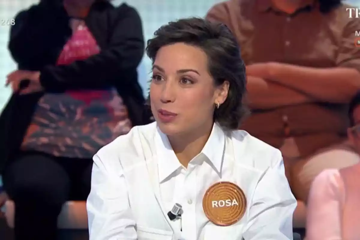 Una persona amb una camisa blanca i un distintiu que diu Una persona amb una camisa blanca i un distintiu que diu
