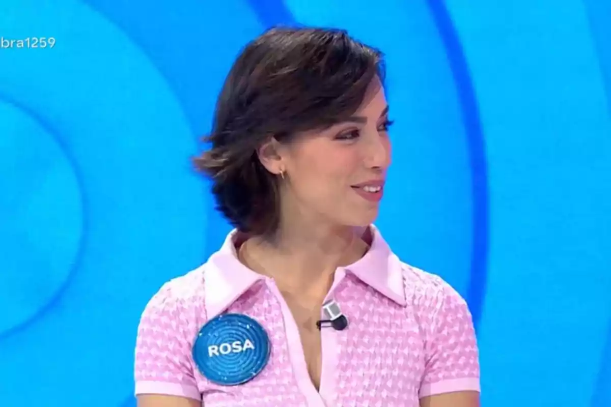 Una persona amb cabell curt i fosc porta una camisa rosa amb un micròfon en un programa de televisió. Una persona amb cabell curt i fosc porta una camisa rosa amb un micròfon en un programa de televisió.