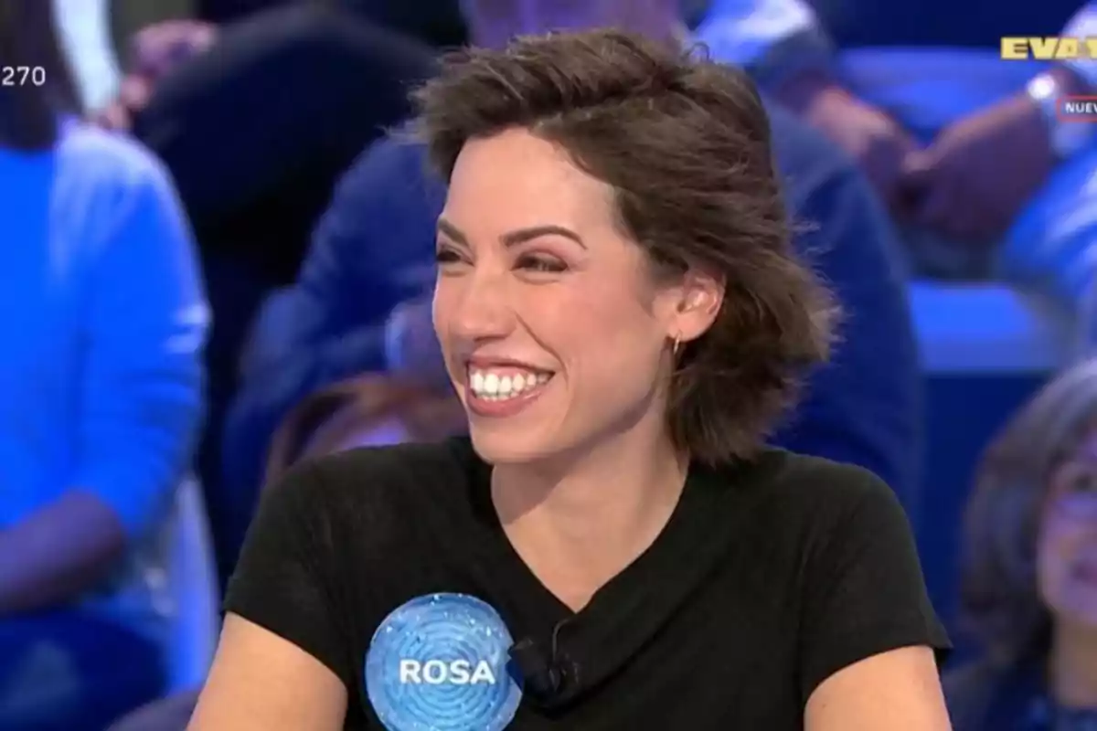 Una persona somrient en un programa de televisió amb un públic de fons. Una persona somrient en un programa de televisió amb un públic de fons.