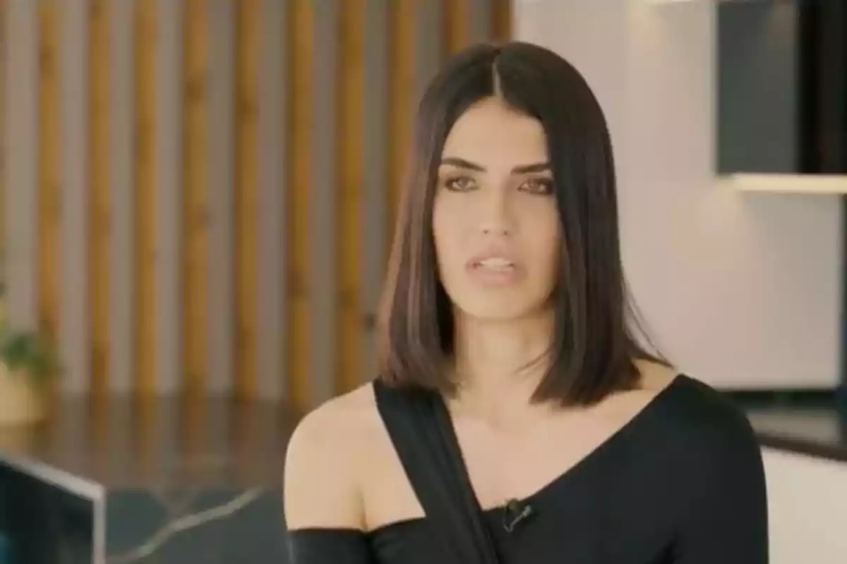 Dona de cabell fosc i laci amb un vestit negre d'una sola espatlla en un entorn interior modern. Dona de cabell fosc i laci amb un vestit negre d'una sola espatlla en un entorn interior modern.