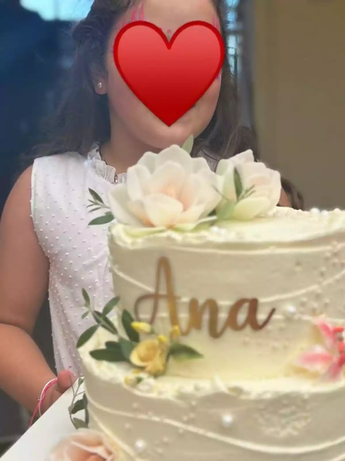Girl in a white dress holding a cake decorated with flowers and the name Ana Girl in a white dress holding a cake decorated with flowers and the name Ana