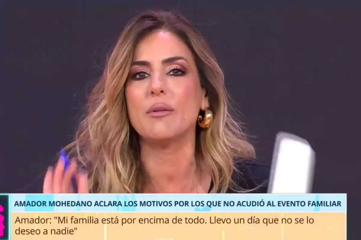 Dona de cabell ros i ondulat amb grans arracades daurades parlant en un programa de televisió amb un rètol informatiu a la part inferior de la pantalla Dona de cabell ros i ondulat amb grans arracades daurades parlant en un programa de televisió amb un rètol informatiu a la part inferior de la pantalla