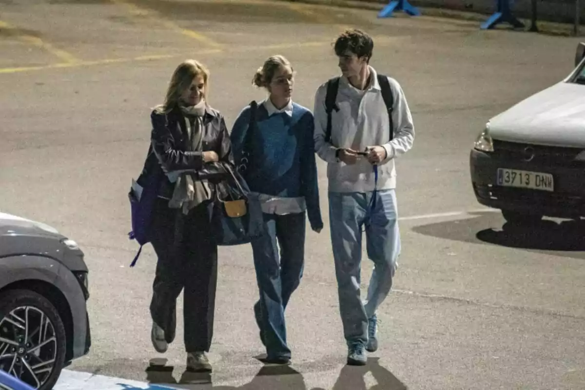 La infanta Cristina, Irene Urdangarin i Pablo Urdangarin caminant juntes en un estacionament il·luminat a la nit.