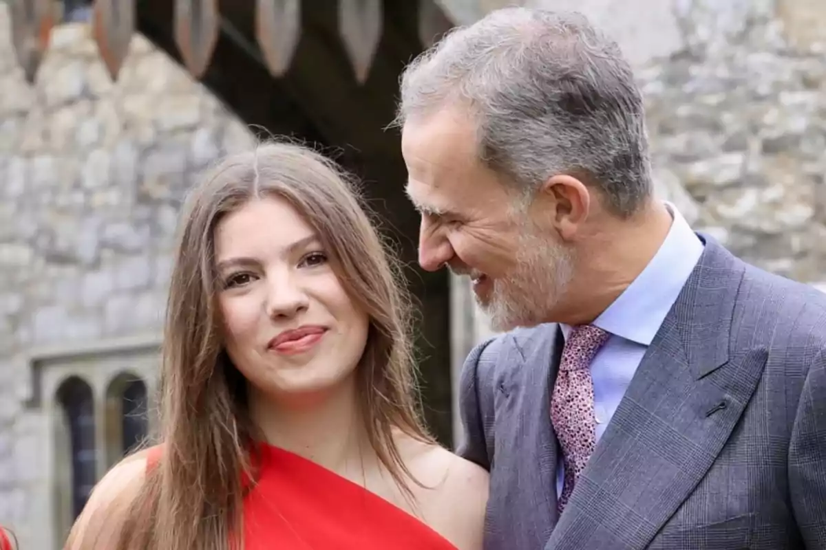 La infanta Sofia, de vermell, somriu mentre el seu pare, el rei Felip, la mira somrient.