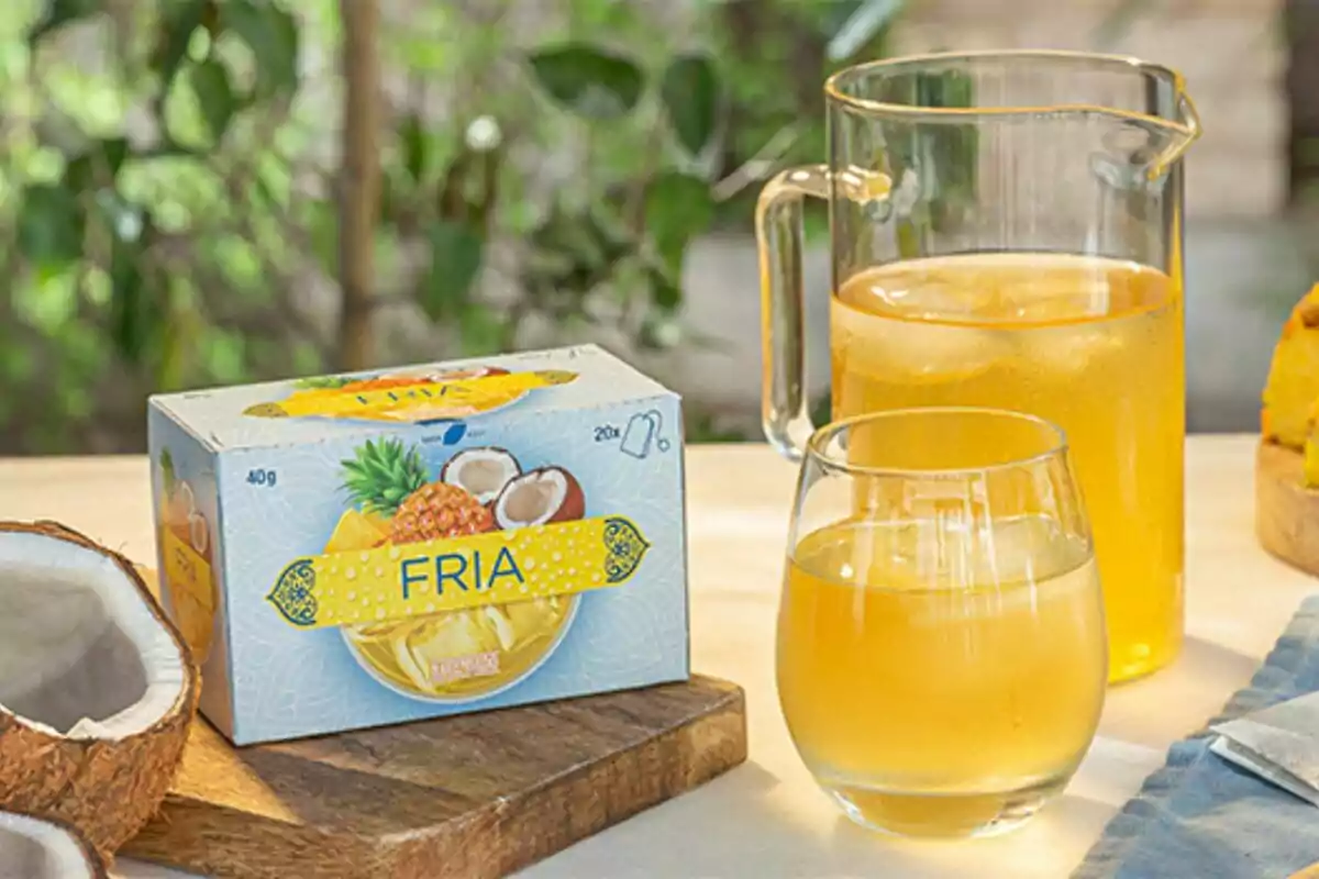 Caixa d'infusió de fruites tropicals al costat d'una gerra i un got amb beguda groga sobre una taula. Caixa d'infusió de fruites tropicals al costat d'una gerra i un got amb beguda groga sobre una taula.