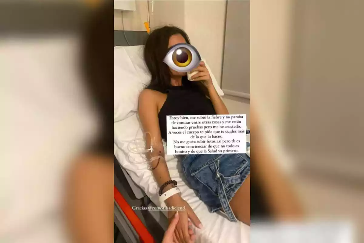 Captura instastory d'Alexia Rivas tumbada a una camilla d'hospital, amb una via a la mà i bebent d'un got. Una emoticona d'un ull li tapa tota la cara. La seva amiga li agafa la mà