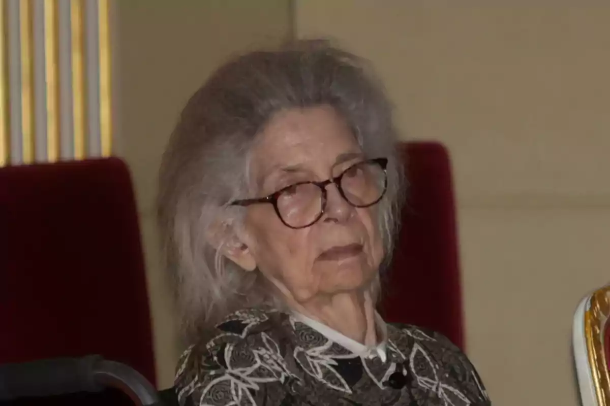 La princesa Irene de Grècia amb ulleres i cabells canosos asseguda en una cadira vermella La princesa Irene de Grècia amb ulleres i cabells canosos asseguda en una cadira vermella