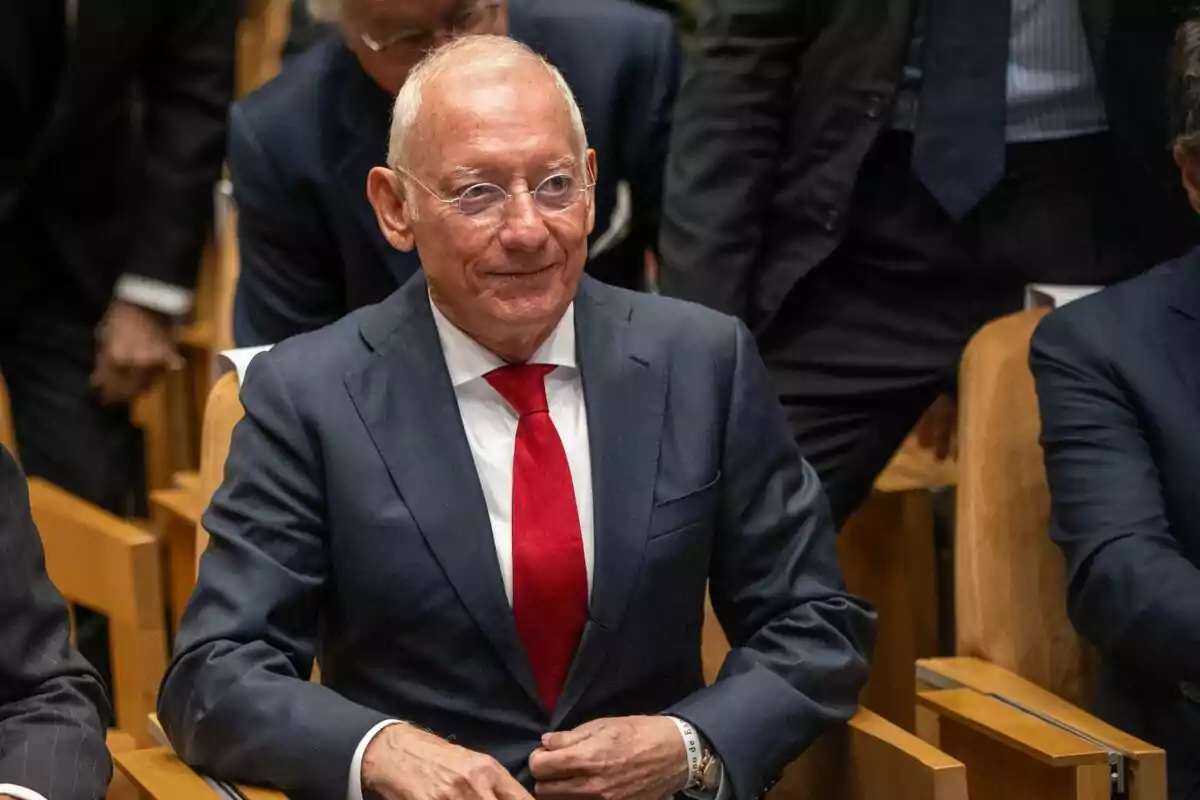 Isak Andic con gafas y traje oscuro con corbata roja sentado en una sala de conferencias.