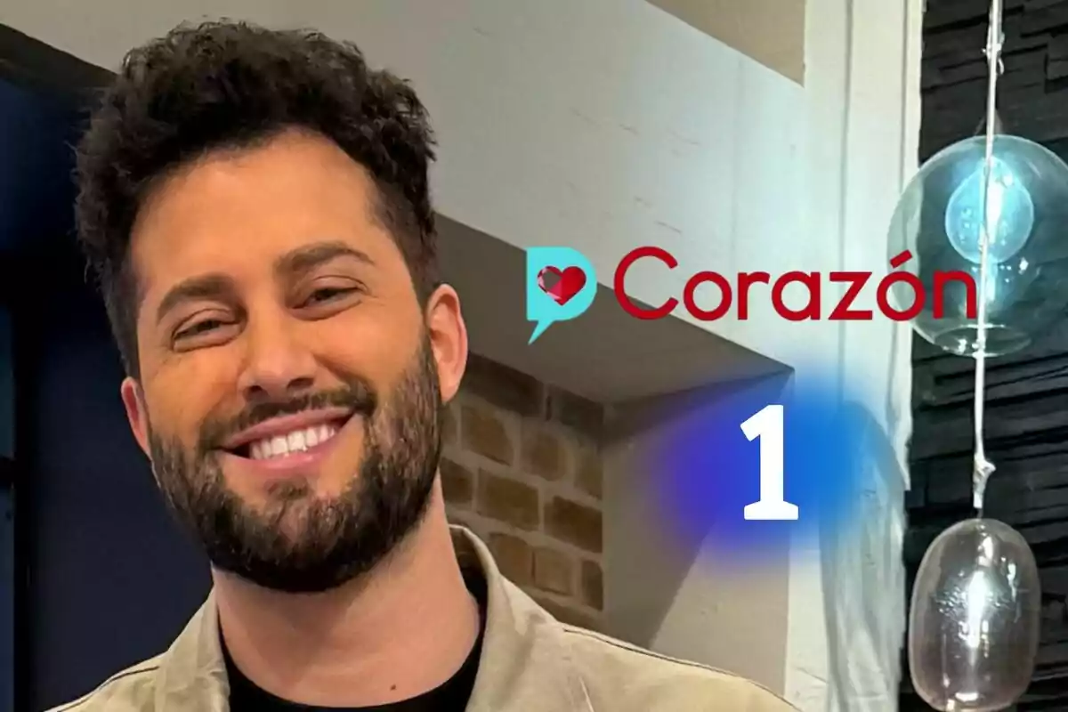 Javi de Hoyos sonriente con barba y cabello rizado en un estudio con el logo de D Corazón y el logo de La 1 al fondo Javi de Hoyos sonriente con barba y cabello rizado en un estudio con el logo de D Corazón y el logo de La 1 al fondo