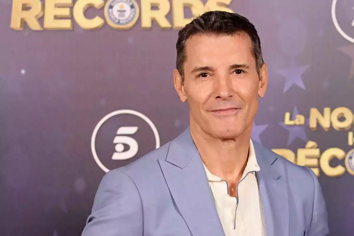 Jesús Vázquez amb vestit clar posa davant d'un fons amb logotips i text relacionat amb La Nit dels Rècords. Jesús Vázquez amb vestit clar posa davant d'un fons amb logotips i text relacionat amb La Nit dels Rècords.