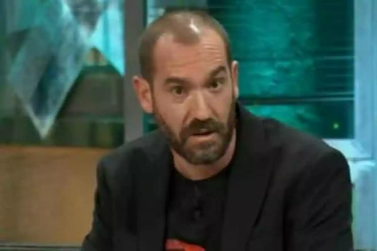 Jorge Ponce amb barba i cabells curts està assegut i sembla estar parlant a La Revuelta amb llums verdes i blaves al fons. Jorge Ponce amb barba i cabells curts està assegut i sembla estar parlant a La Revuelta amb llums verdes i blaves al fons.